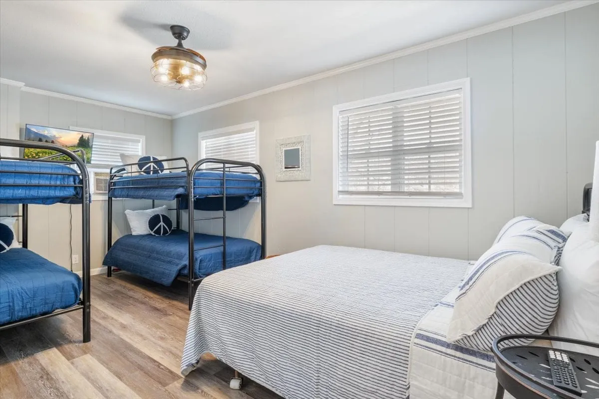 A versatile bedroom with a double bed plus bunk beds, a decorative wall mirror, and a stylish light fixture. The space is relaxed and inviting, perfect for families or groups traveling together and seeking both comfort and flexible sleeping arrangements.