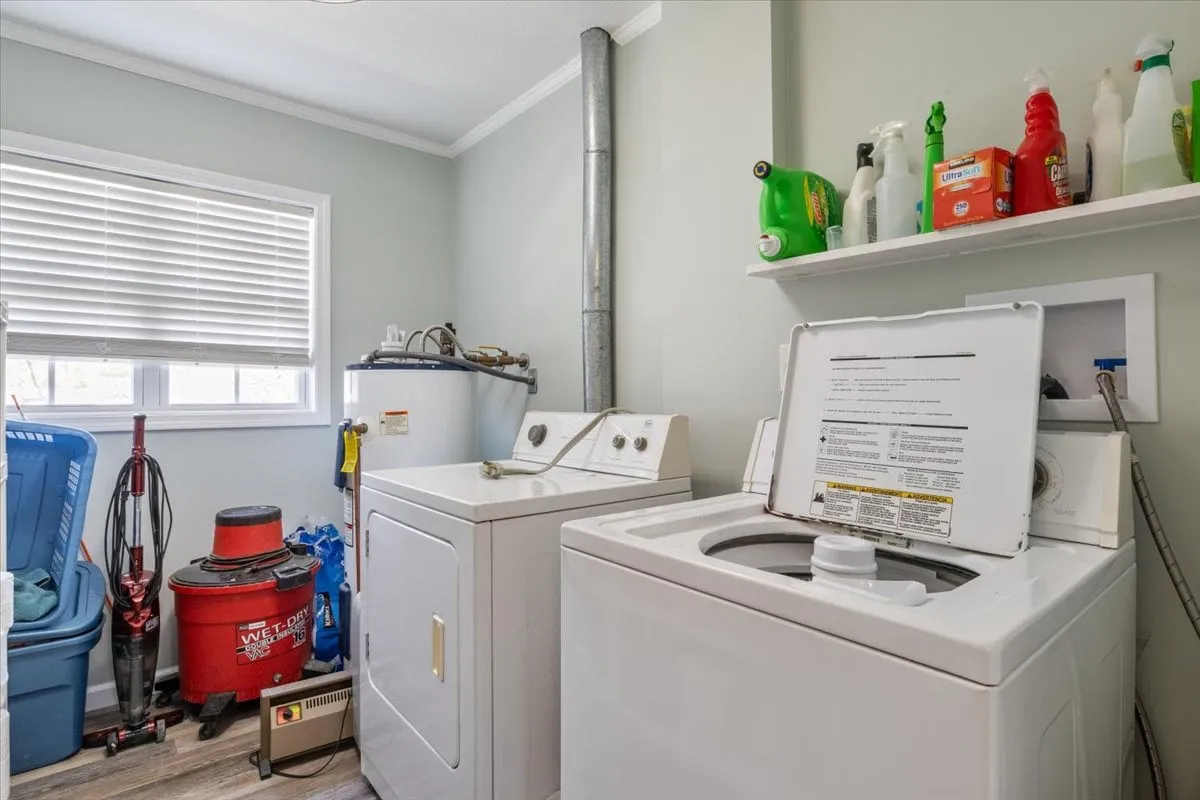 A tidy laundry area with washer and dryer, cleaning supplies, and organized storage bins. The space is functional and easy to access, supporting practical needs during a family's stay.