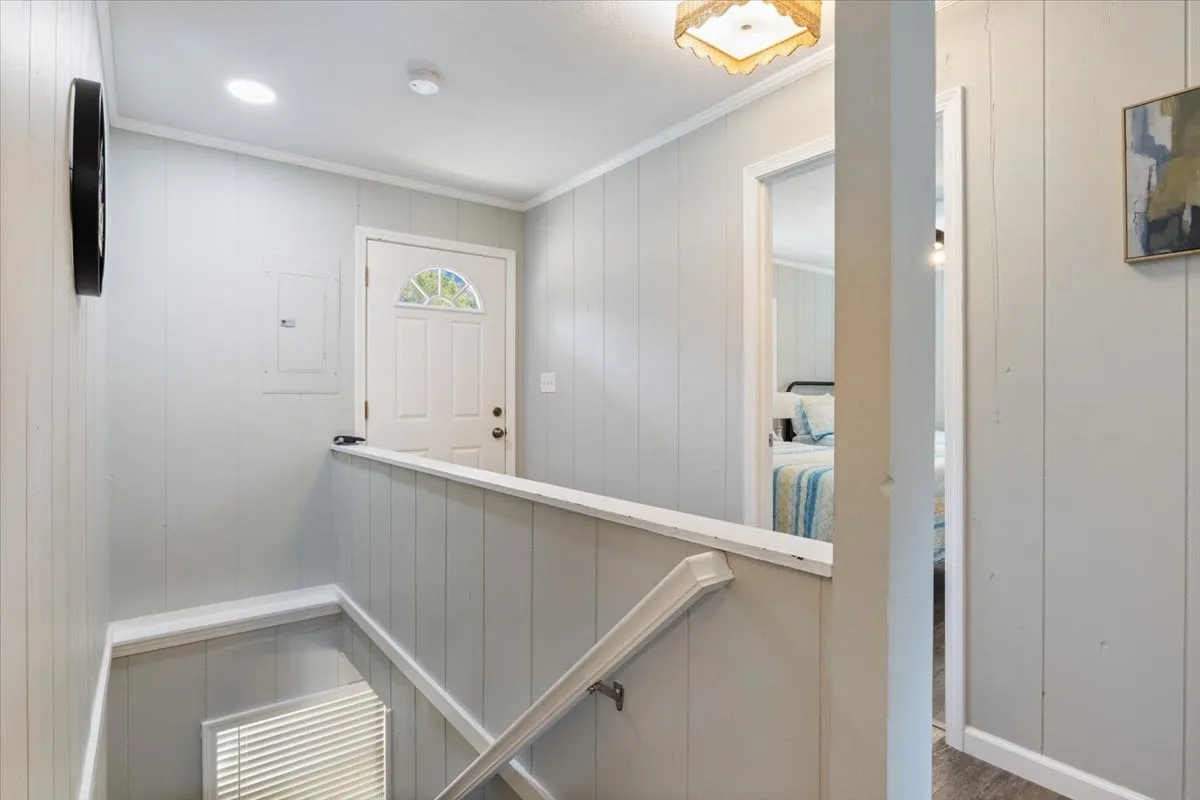 A welcoming entryway featuring a front door, a staircase leading to the upper floor, and a tasteful art piece on the wall. The scene feels open and homey, suggesting a well-cared-for and inviting environment right as guests enter.