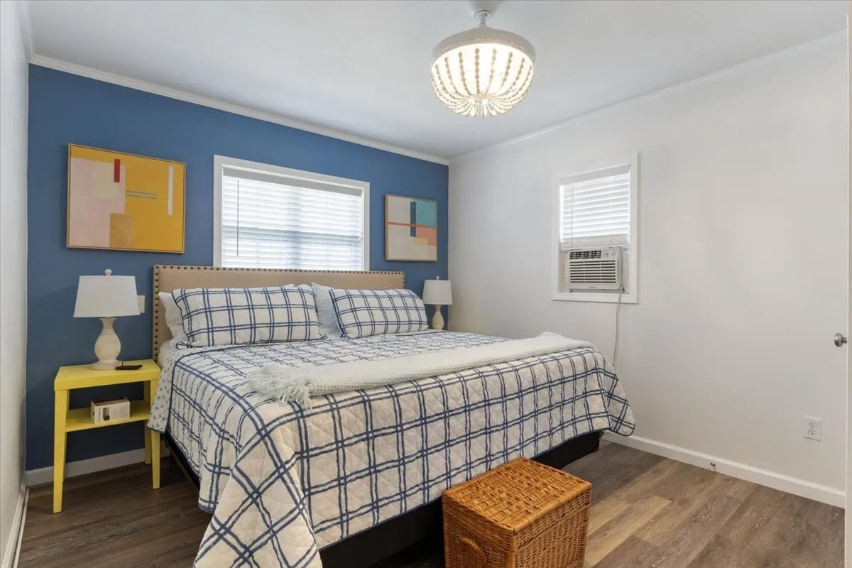 A tranquil bedroom featuring a comfortable bed with soft bedding, calming artwork on the walls, and nightstands on either side. Gentle natural light streams into the room, creating a peaceful and inviting atmosphere ideal for relaxation and rest.