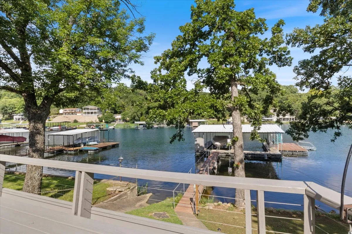 A serene panoramic view of the lake with docks stretching into the water and trees lining the shore. The calm surface reflects the sky, and the scene exudes tranquility and the spirit of Osage Beach's lakeside lifestyle.